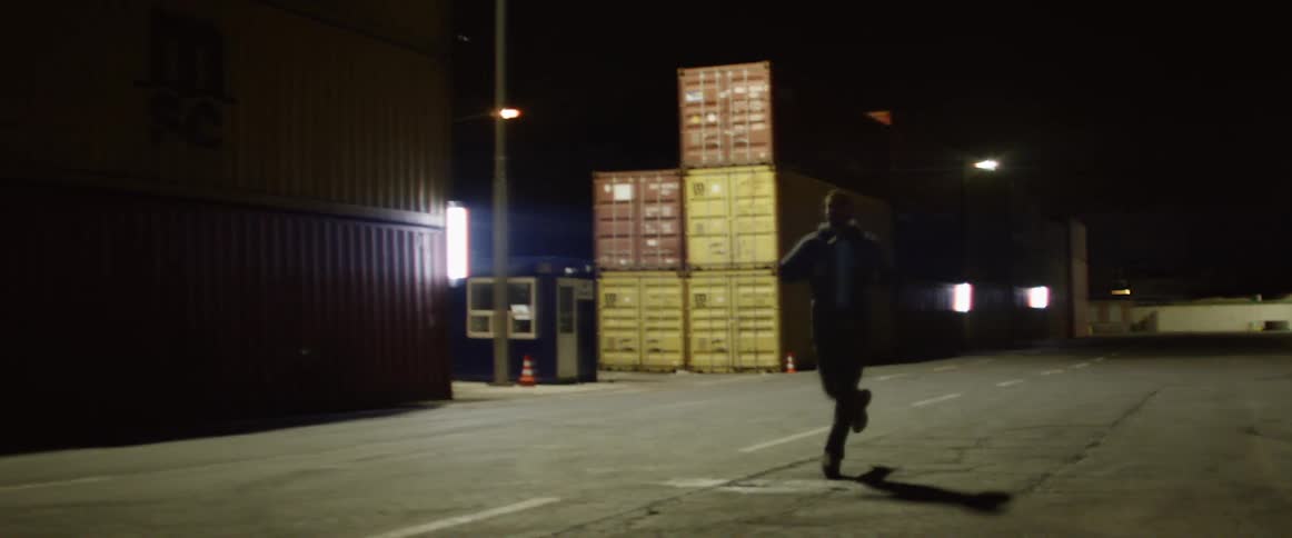 A man runs past a warehouse in a lot
