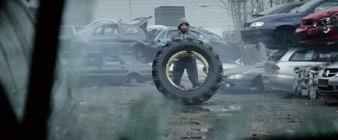 A man doing workout by lifting a truck wheel