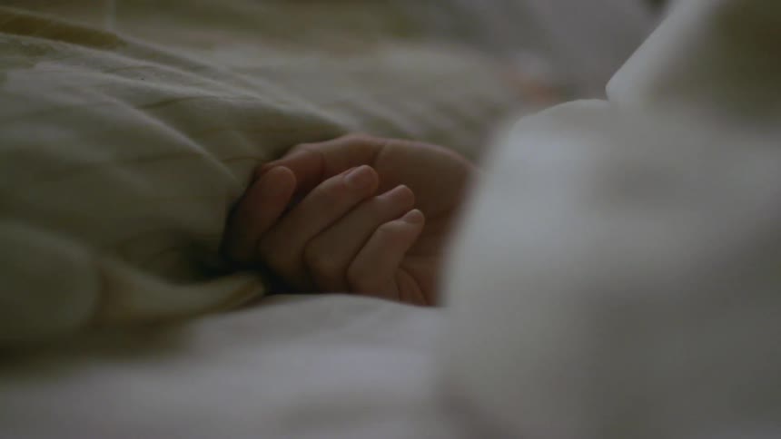 A hand lying next to a pillow