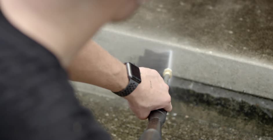 A man power washes the concrete