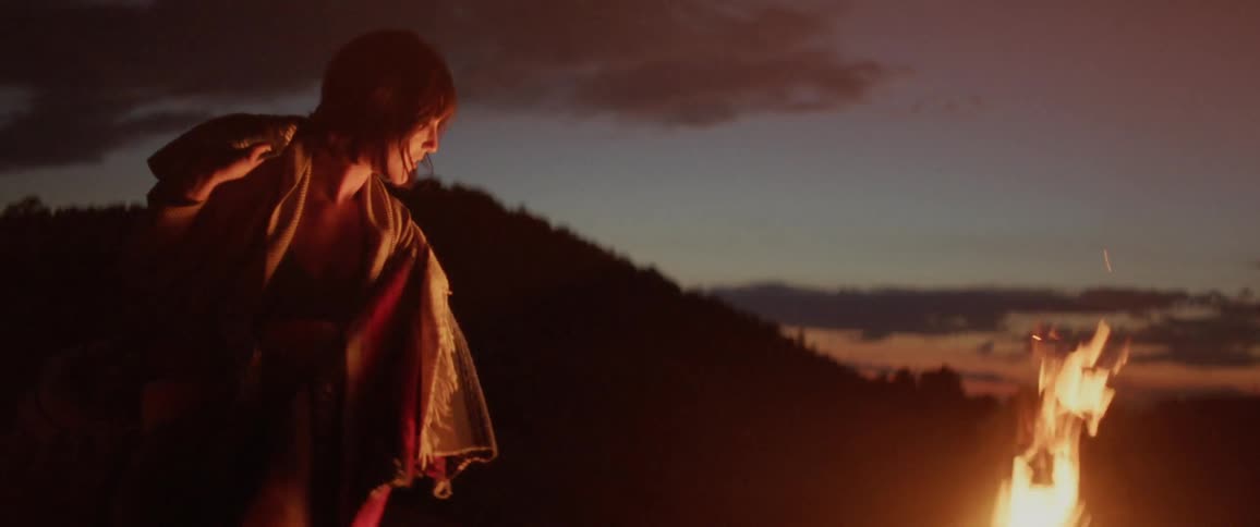 Woman swings her poncho over a bonfire