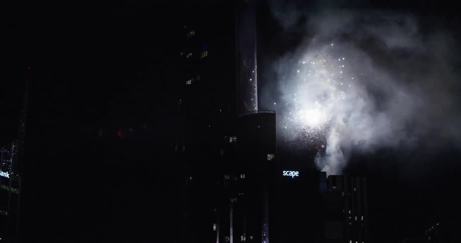 Sparkling fireworks bursting over buildings at night