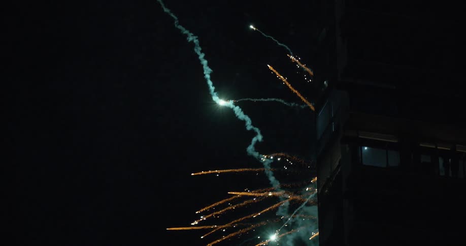 The fireworks shoot behind the building at night
