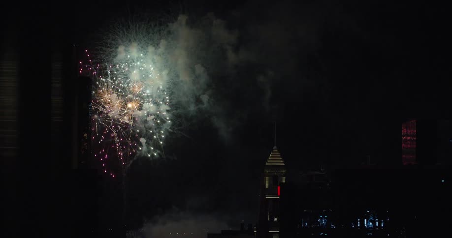 Fireworks explode in the sky over a large city
