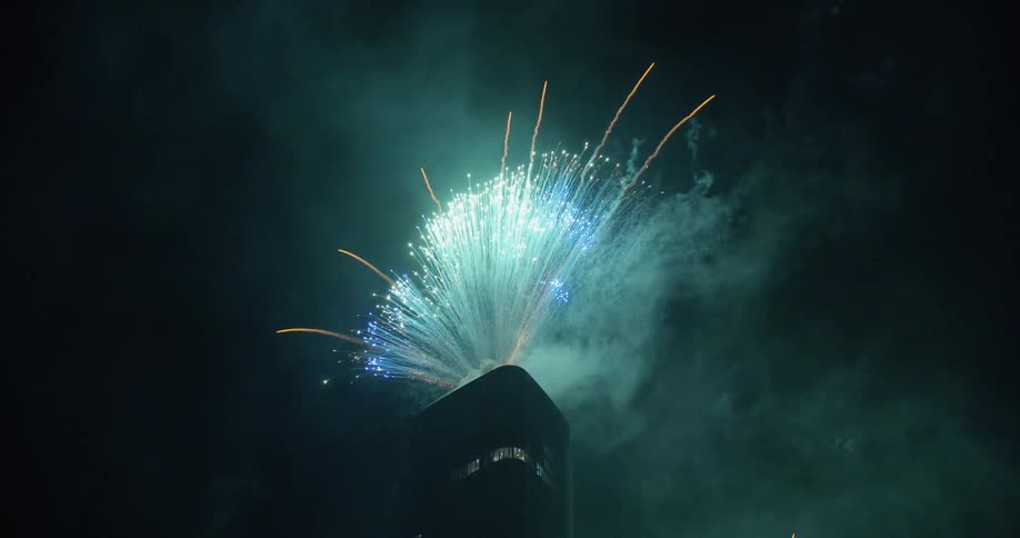 Fireworks explode into the night sky over skyscraper