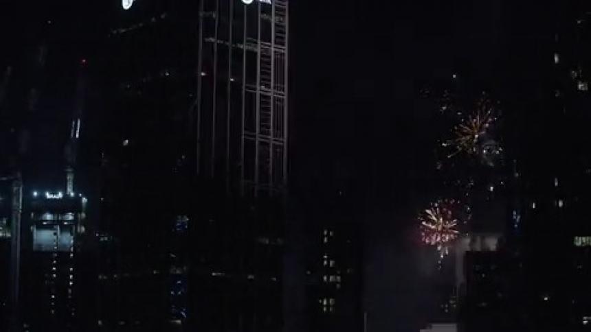 Fireworks explode in the dark sky above a city