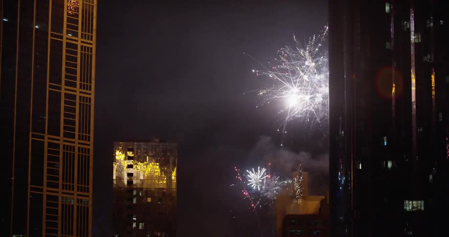 Fireworks are set off into the sky above the city buildings at night