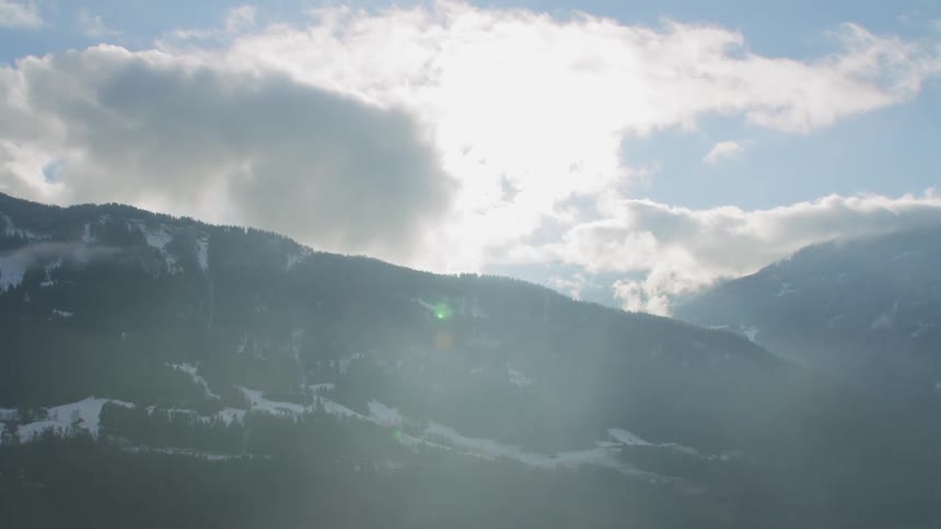 Sunlight falls over a heavily forested mountain range