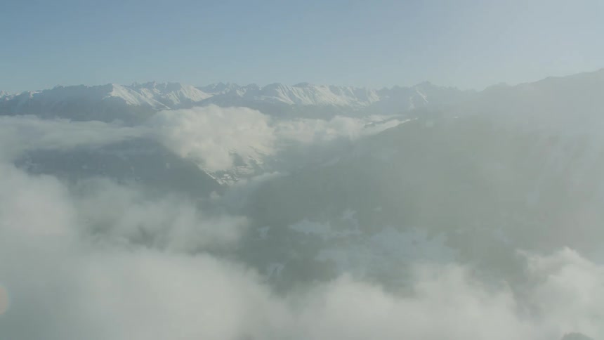 A snow capped mountain range seen through the clouds