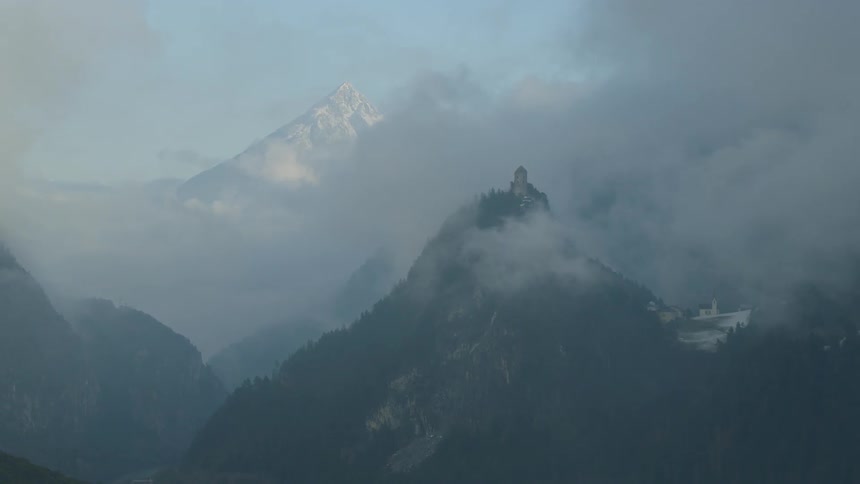 Aerial view of castle on mountain top surrounded by clouds