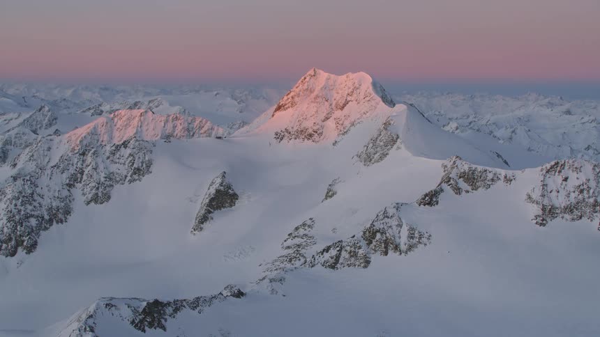 The sun sets on the snow covered mountain