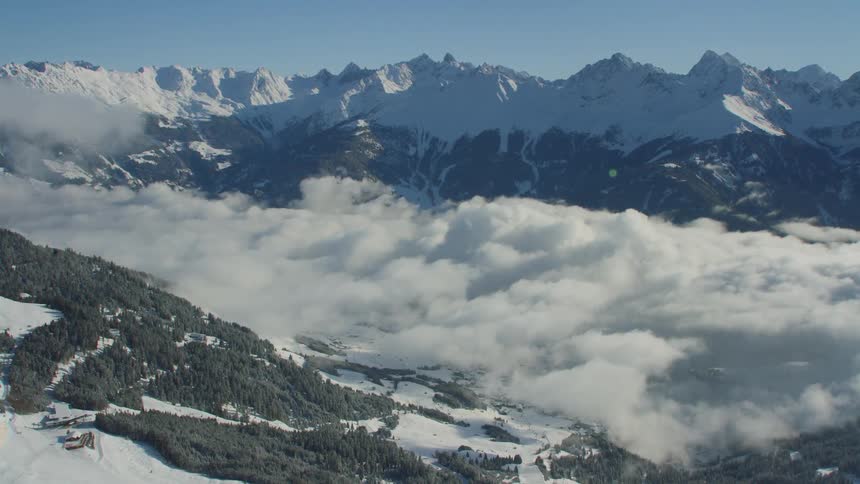 A valley between snowy mountain ridges shrouded in clouds