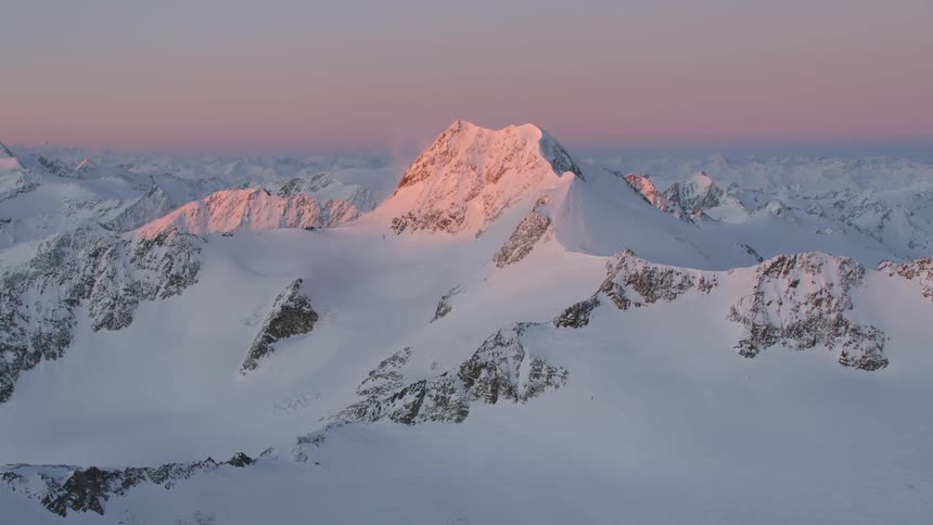 Aerial of snow covered mountain peaks at sunrise