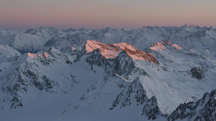 Sun highlights peak among snow covered mountain range