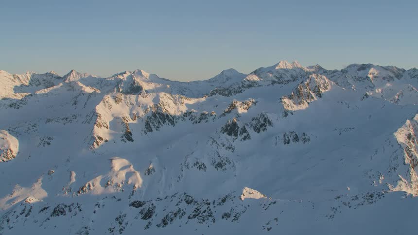 The sun rises over a snow covered mountain range