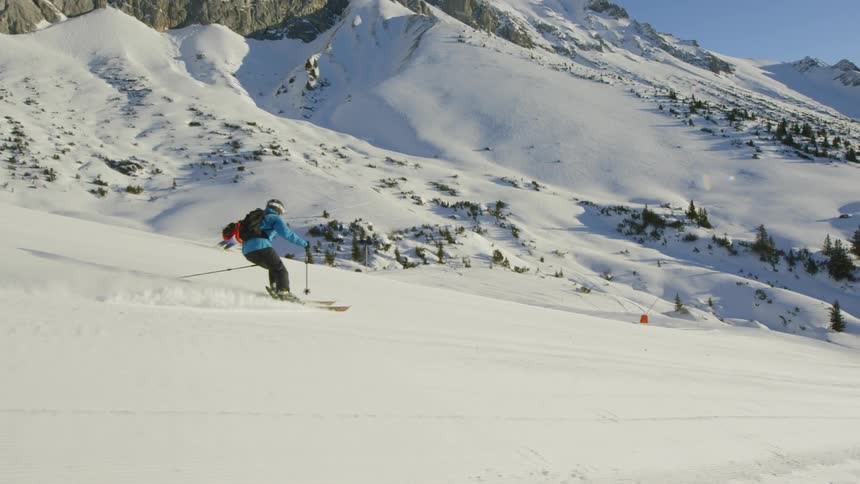 Two people ski down a course on a snowy mountain