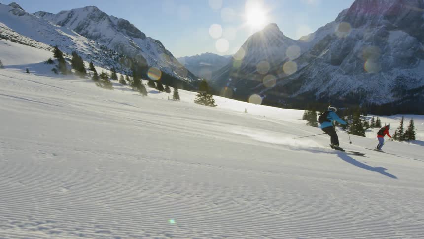 Skiers glide down a steep slope