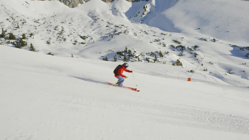 A skier zigzagging down a snowy slope during the day