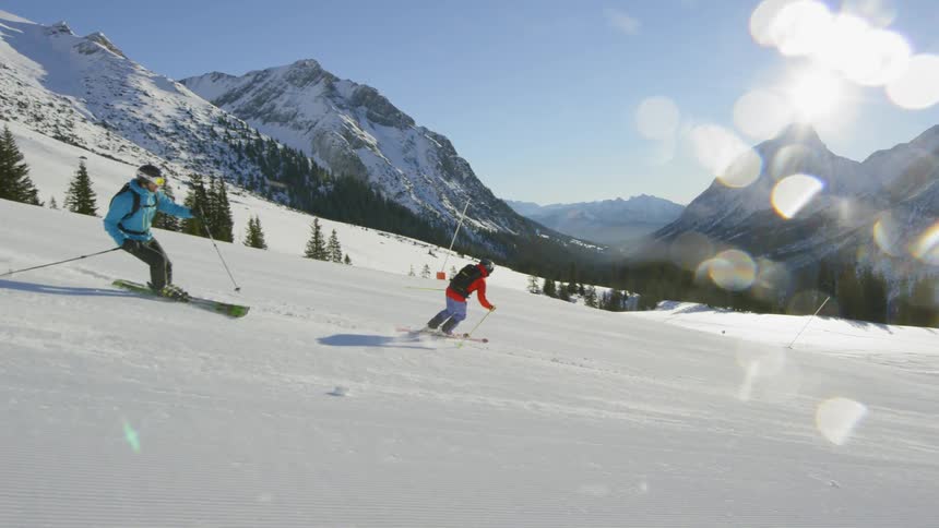 Two people ski down the mountain