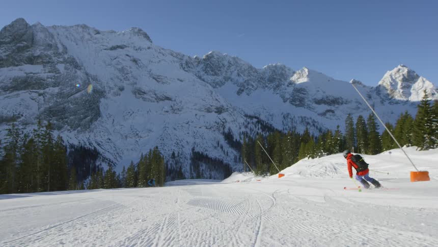 Skier skiing down a groomed run at mountain resort