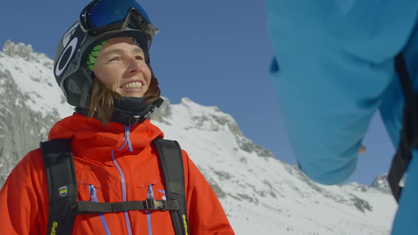 Two people are talking together while wearing winter sport outfits