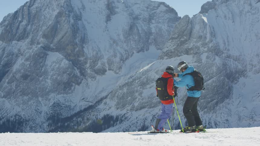 Skiers taking a selfie with a cell phone on a ski run in the mountains