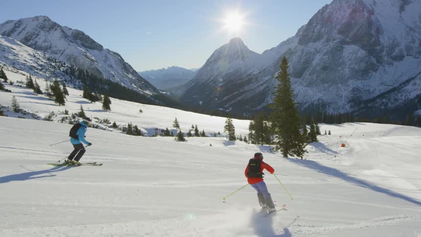 A pair of skiers descending a ski slope during the day
