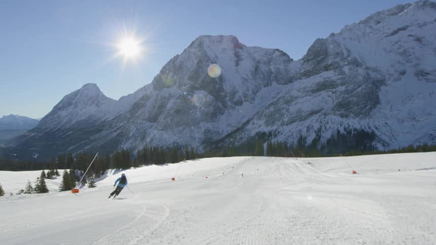 A skier races down a snow covered ski slope