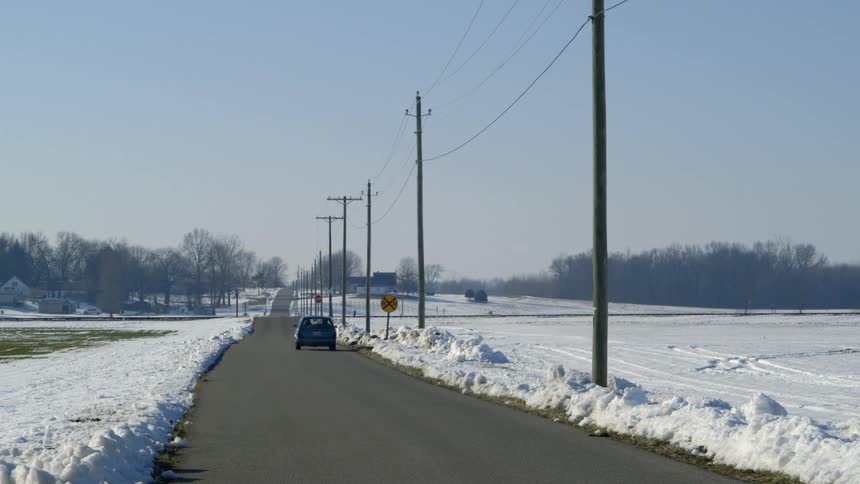 A car driving down a road surrounded by snow