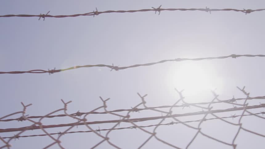 View of a sun through barbed wire