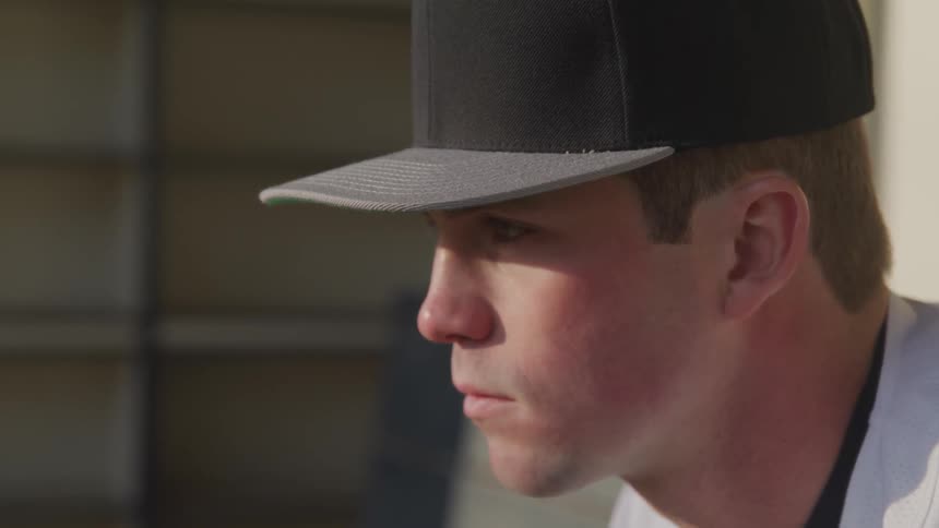 Baseball player wearing baseball cap sitting on bench