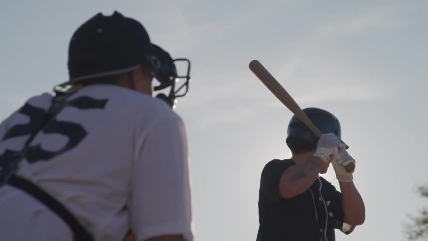 A male holds up a baseball bat getting ready to swing
