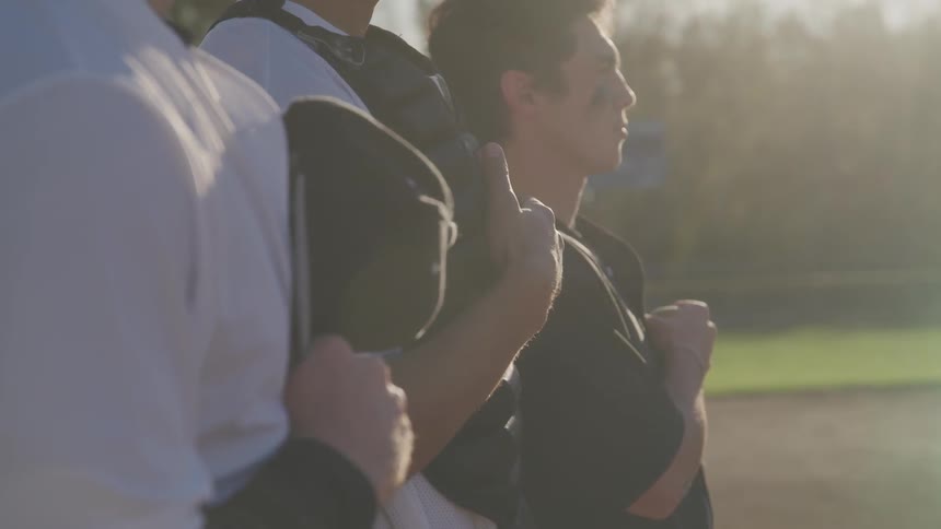Three baseball players stand for the pledge of allegiance