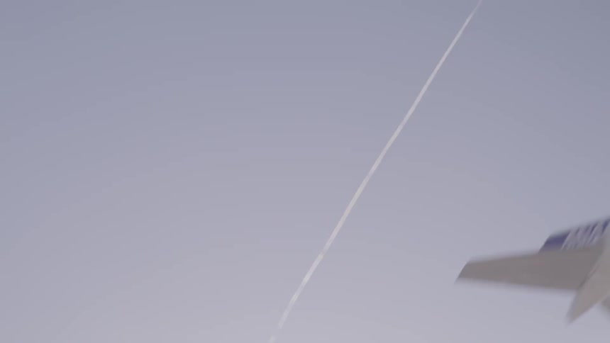 A passenger plane soars quickly across the sky while leaving a thin contrail behind it