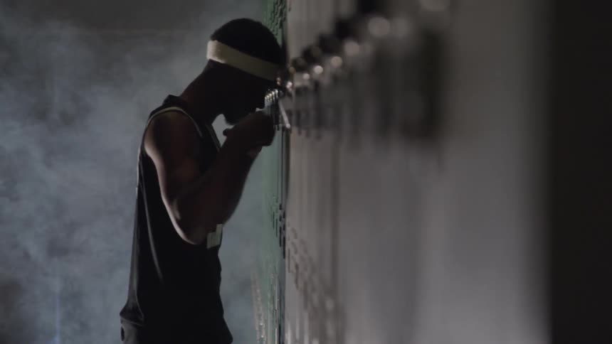 Basketball player leans against locker and hits lightly
