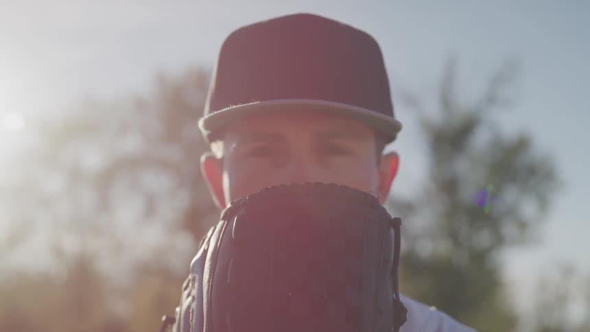 A portrait of a man with baseball gloves under the sun flare