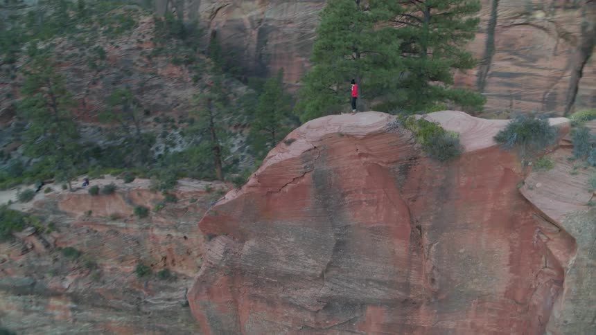 A person stands on an extremely high mountain cliff edge