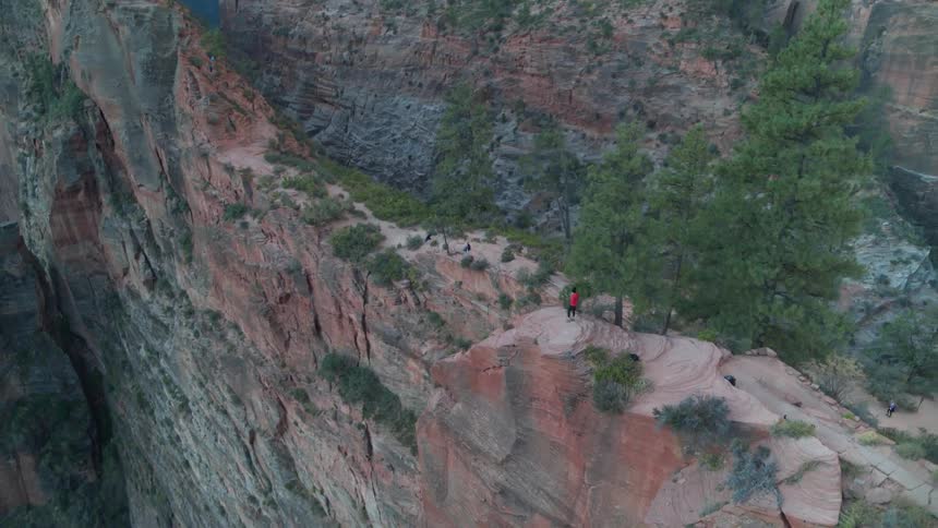 A person stands on the ridge of a sheer cliff