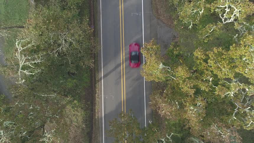 Red car drives on road during the day