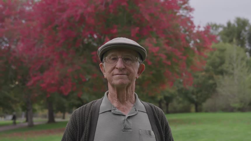 An elderly man stands in park