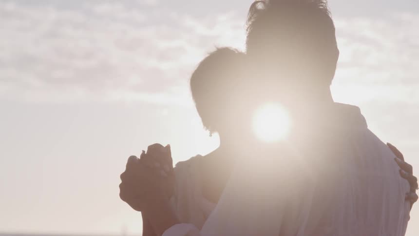 Couple dances on beach under cloudy sky