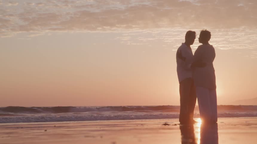 A couple dancing on the beach at the sunset