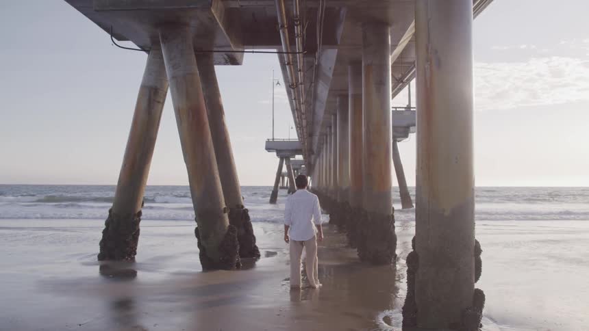 Man stands under pier between support beams