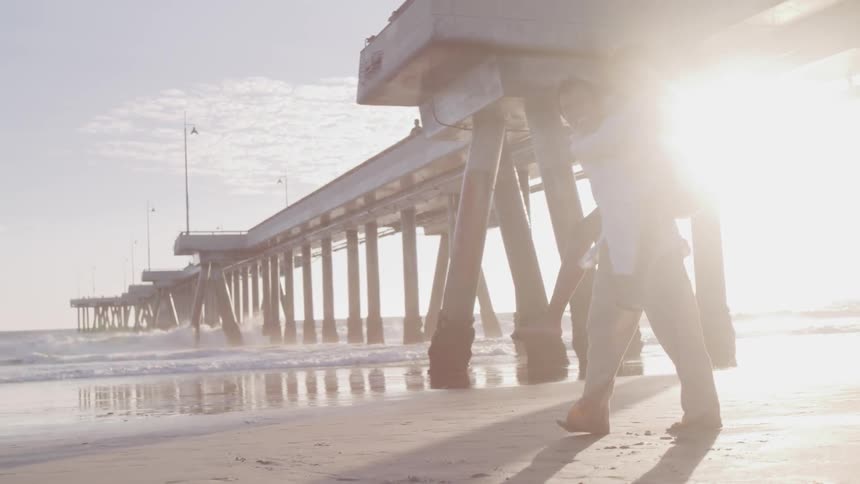 A man piggy backing his woman on the beach