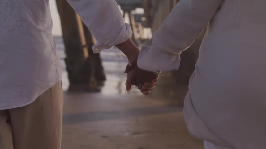 A couple with white shirt holding hand on the beach