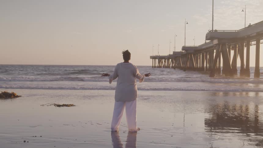 A man doing a yoga on the beach at the dawn