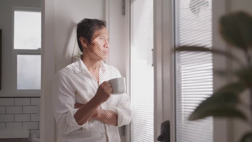 A man is drinking coffee by the window
