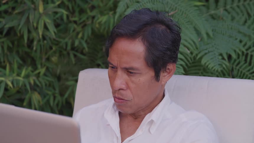 A middle aged man working with his laptop at the garden