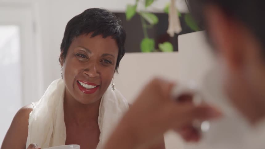 An older black woman smiles while looking at a man
