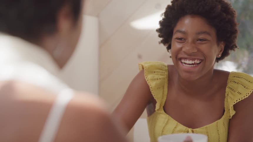 Two women talking and laughing while drinking hot beverage